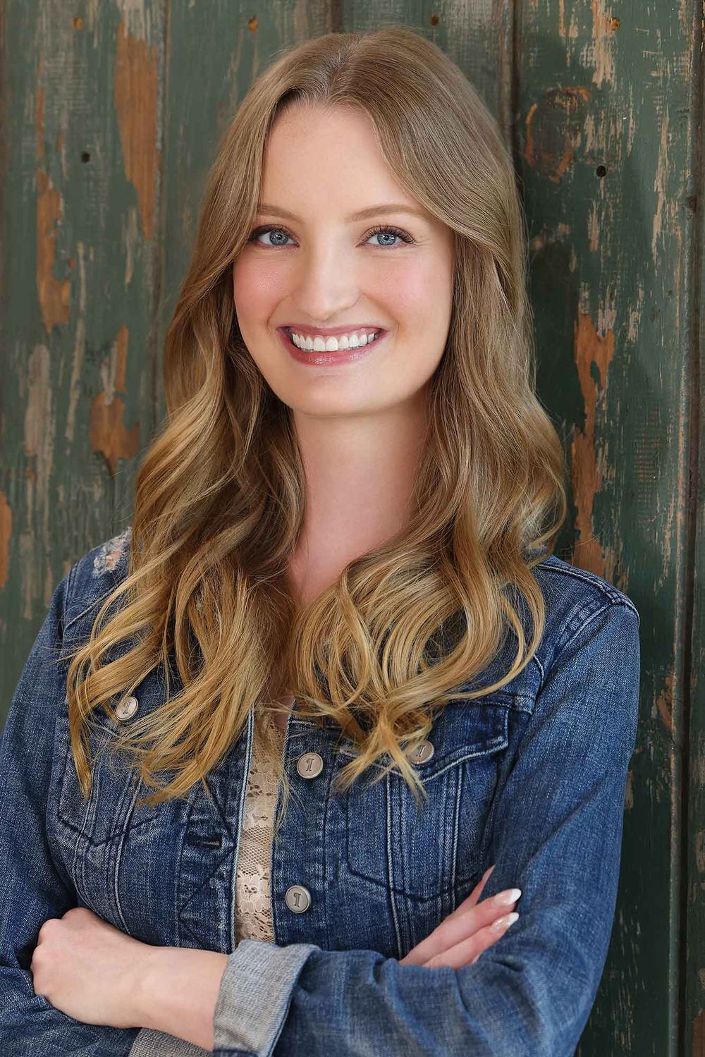 Chelsey Kaye smiling in a denim jacket, arms crossed